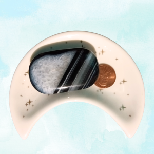 Black Agate Geode Palm Stone, in moon-shaped dish, light background