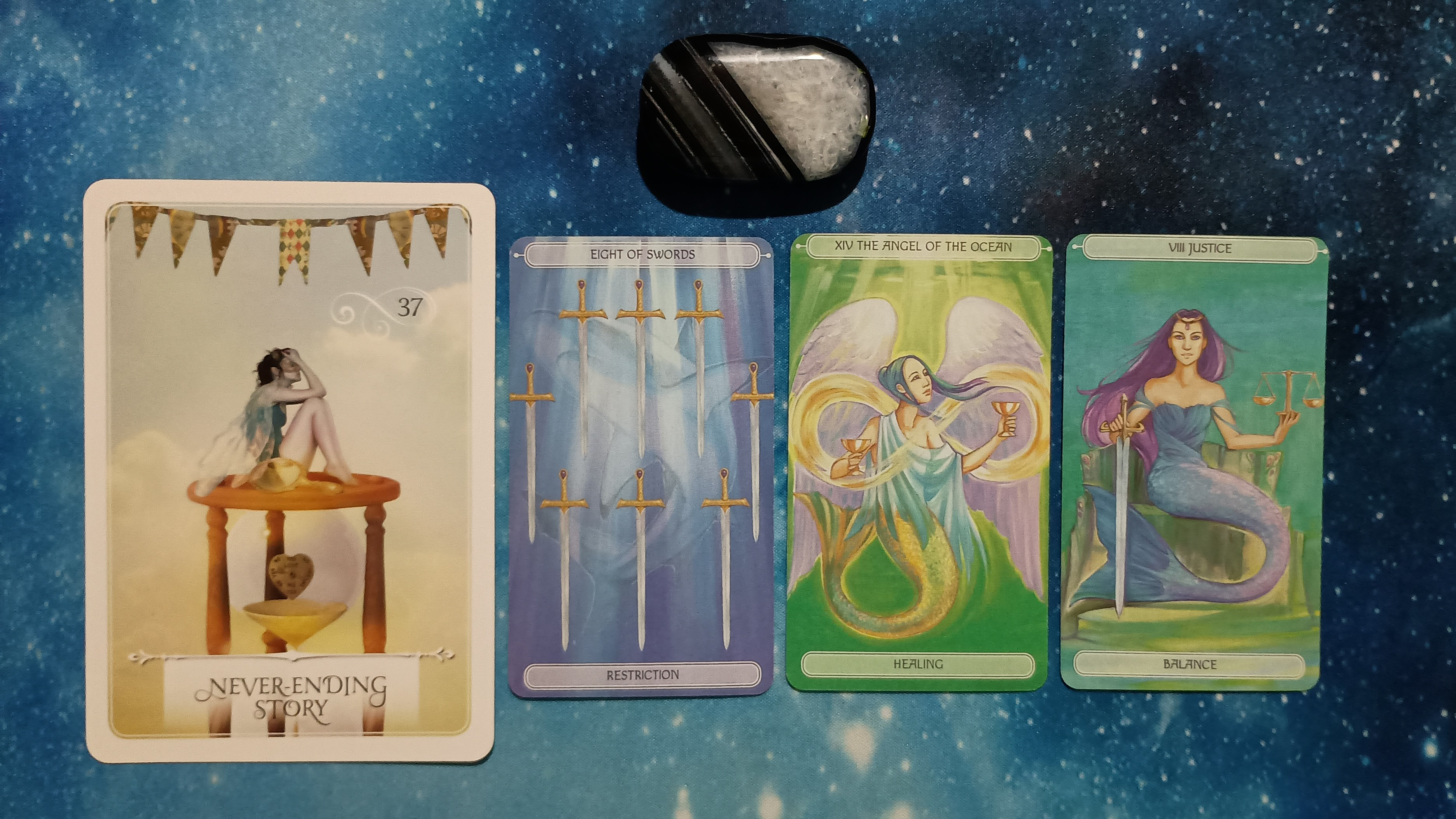New Moon Pick-a-Card Tarot Reading for May 2025, pile 2 - Black Agate stone and 4 cards on a starry blue background