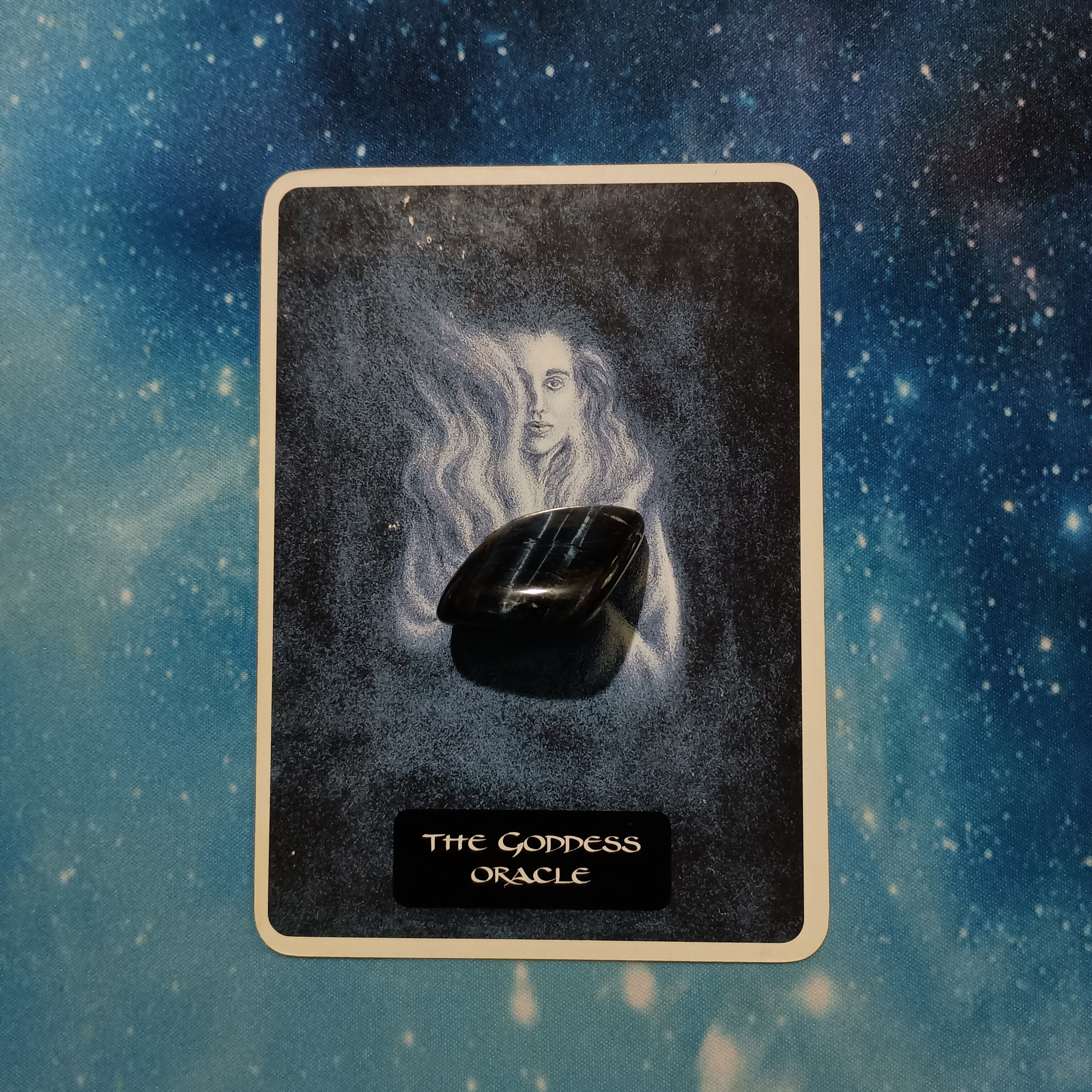Full Moon Pick-a-Card Tarot Reading for July 2025, Pile 3, Blue Tiger’s Eye crystal (Black with blue flash) on 1 oracle card, face down