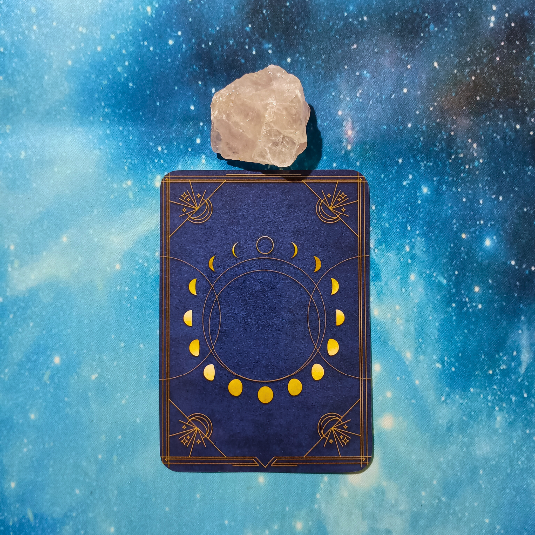 New Moon Magic: Your August 2025 Pick-a-Card Tarot Reading, pile 1 — rose quartz (pink) stone and an oracle, face down on a starry blue background