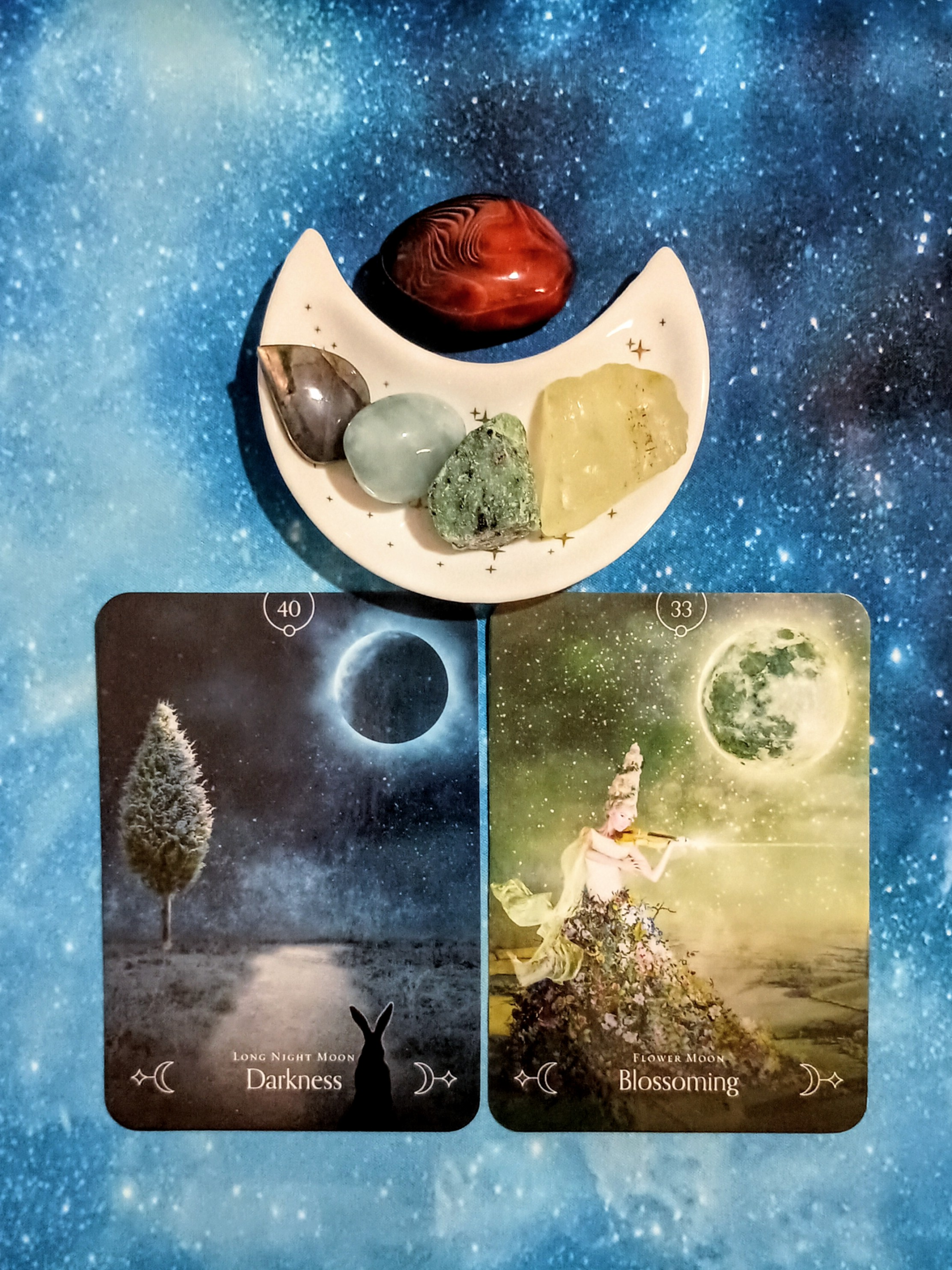 New Beginnings, New Energy: A Message From the Universe, 2 Queen of the Moon Oracle cards and crystals on a starry blue background